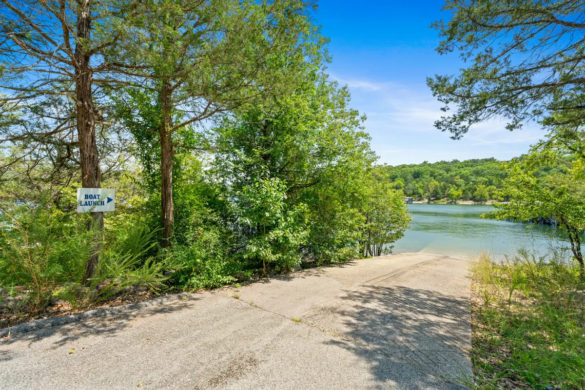 A boat launch sign marks a concrete ramp leading down to the water, framed by greenery and offering a glimpse of the lake. The scene suggests access for boating, fishing, and lakeside picnics, reinforcing the property's connection to Table Rock Lake and its outdoor possibilities.