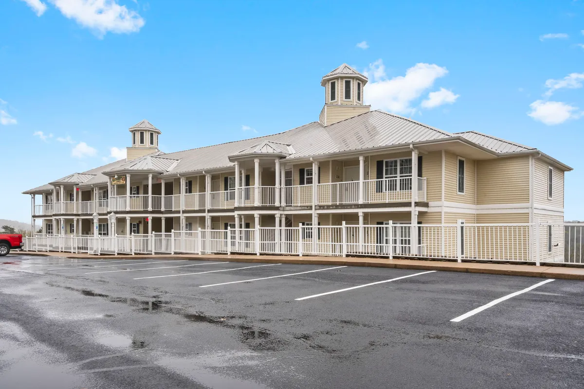 The exterior of the building with clear views of multiple balconies, each offering personal outdoor spaces. The image also captures architectural features of the property and a welcoming parking area below, with soft light suggesting a calm, inviting atmosphere.